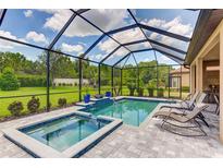 Screened pool area with spa, tiled deck, and lush landscaping offers a relaxing outdoor space at 9769 Highland Park Pl, Palmetto, FL 34221