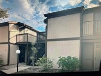 Two-story condo featuring neutral stucco, dark trim, wooden balconies, and manicured shrubbery at 4022 Beaver Ln # 1000G, Port Charlotte, FL 33952
