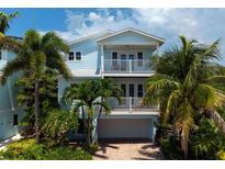 Two-story light blue house with balcony, palm trees, and a two-car garage at 4805 2Nd Ave, Holmes Beach, FL 34217