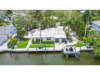 Aerial view of waterfront home with boat lift and lush landscaping at 562 Juan Anasco Dr, Longboat Key, FL 34228