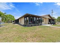 Tan single-story home with sunroom and grassy yard at 4109 66Th Street W Cir # 4109, Bradenton, FL 34209