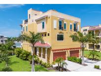 Beautiful three-story yellow home with two-car garage, lush landscaping, and a red tile roof at 1450 Silvia Shores Dr, Apollo Beach, FL 33572