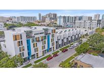 Modern townhomes featuring colorful accents line a city street with lush trees and parked vehicles at 1558 4Th St # 216, Sarasota, FL 34236