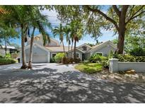 Gray house with palm trees, driveway, and landscaped yard at 1400 Quail Dr, Sarasota, FL 34231