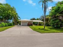 Charming single-story home with lush landscaping, bright white exterior, and a well-maintained front lawn at 302 Mendez Dr, Sarasota, FL 34243