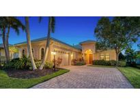 Attractive single-story home with a brick driveway and landscape lighting at 14717 Leopard Creek Pl, Lakewood Ranch, FL 34202