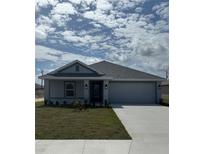 Charming single-story home featuring a two-car garage and a well-manicured lawn under a sunny, partly cloudy sky at 2628 Averland Loop, North Port, FL 34287