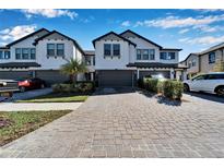 Two-story townhome with gray brick driveway and landscaping at 4564 Almada Ln, Wesley Chapel, FL 33543