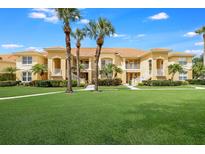 Two-story condo building with lush landscaping and palm trees at 7187 Boca Grove Pl # 202, Lakewood Ranch, FL 34202