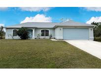 Single-story home with light gray exterior, two-car garage, and landscaped lawn at 2415 Ancient Rd, North Port, FL 34286