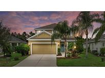 Two-story house with tan siding, a two-car garage, and landscaped yard at 12224 Longview Lake Cir, Bradenton, FL 34211