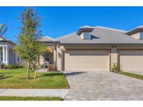 Tan two-car garage villa with paved driveway and landscaped lawn at 17890 Cherished Loop, Bradenton, FL 34211