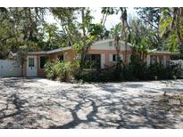 Light peach house with white trim, surrounded by lush tropical landscaping at 144 Garden Ln, Sarasota, FL 34242