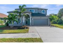 Inviting two-story home featuring a two-car garage, beautiful landscaping, and a welcoming front porch at 1868 Scarlett Ave, North Port, FL 34289