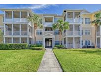 Inviting condo building featuring multiple stories, screened patios, well-manicured lawns, and mature palm trees at 4802 51St W St # 908, Bradenton, FL 34210