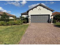 House exterior features a gray-toned home with a 2-car garage, landscaping and paver driveway at 4747 Motta Ct, Bradenton, FL 34211