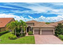 Single-story home with tile roof, brick driveway, and lush landscaping at 11192 Whimbrel Ln, Sarasota, FL 34238