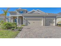 Two-story house with light beige siding, three-car garage, and landscaped yard at 21205 Holmes Cir, Venice, FL 34293