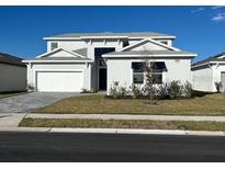 Two-story home with gray exterior, three-car garage, and landscaped yard at 8324 Golden Beach Ct, Parrish, FL 34219