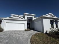 Modern two-story home with gray exterior, three-car garage, and paver driveway at 8324 Golden Beach Ct, Parrish, FL 34219