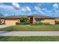 Single-story home featuring an attached garage, brick accents, and mature landscaping at 4918 Fallcrest Cir, Sarasota, FL 34233