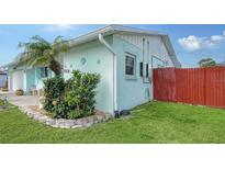 Charming home featuring a well-maintained lawn, vibrant flower beds, and a colorful red fence for added curb appeal at 1080 Piedmont Rd, Venice, FL 34293
