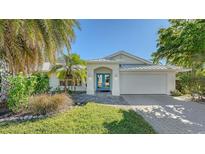Charming single-story home with vibrant blue double-door entry, manicured landscaping, and a convenient two-car garage at 435 Partridge Cir, Sarasota, FL 34236