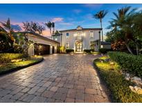 Elegant two-story home with a paver driveway and lush landscaping at 65 Lighthouse Point Dr, Longboat Key, FL 34228