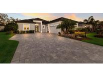 Two-story home with a gray facade, paver driveway, and landscaping at 9908 Carnoustie Pl, Bradenton, FL 34211