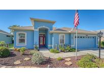 Single-story home with red door, landscaped yard, and attached garage at 10643 Old Grove Cir, Bradenton, FL 34212