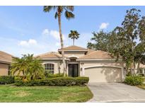 Tan one-story house with a two-car garage and lush landscaping at 9143 Willow Brook Dr, Sarasota, FL 34238