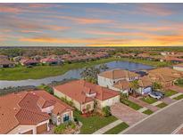 Aerial view of a luxury community with lake, sunset, and multiple homes at 20717 Benissimo Dr, Venice, FL 34293