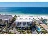 Aerial view of a modern condominium complex on a pristine white sand beach with clear blue ocean views at 1035 Seaside Dr # 305, Sarasota, FL 34242