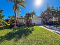 Single-story home with a landscaped lawn, palm trees, and a paved driveway at 4854 Sabal Lake Cir, Sarasota, FL 34238