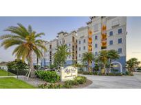 Beautiful condo building featuring a branded sign, palm trees, well-maintained landscaping, and colorful facade at 505 Tamiami N Trl # 201, Venice, FL 34285