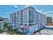 Modern high-rise condo building featuring balconies, palm trees and vibrant mural, under a blue sky at 111 S Pineapple Ave # 1018, Sarasota, FL 34236
