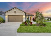 Single-story home with a two-car garage, landscaped yard, and sunset view at 12735 Aquamarine Ave, Bradenton, FL 34211