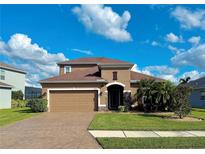 Two-story house with tan exterior, brown roof, and a two-car garage at 7926 111Th E Ter, Parrish, FL 34219