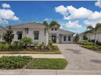 Two-story home with gray exterior, paver driveway, and landscaping at 8372 Sea Glass Ct, Sarasota, FL 34240