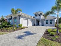 Two-story home with gray exterior, three-car garage, and paver driveway at 8372 Sea Glass Ct, Sarasota, FL 34240