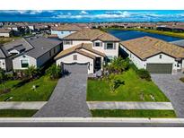 Two-story home with paver driveway, landscaping, and lake view in a community setting at 15511 Islandwalk Ave, Bradenton, FL 34211