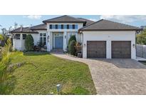 Two-story home with light-colored siding, a three-car garage, and a landscaped yard at 609 Colonial Bay Dr, Nokomis, FL 34275