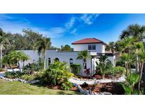 White stucco house with red tile roof, lush landscaping, and a walkway at 2402 Palmetto St, Nokomis, FL 34275