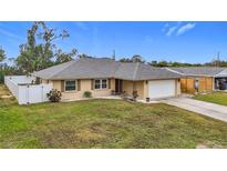 Tan one-story house with gray roof, white fence, and driveway at 161 Sandhurst Dr, Venice, FL 34293