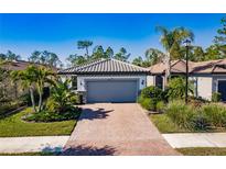 One-story house with gray garage door and a brick driveway, surrounded by landscaping and other homes at 2479 Brassica Dr, North Port, FL 34289
