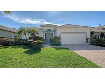 Single-story home with a two-car garage, lush landscaping, and a paved driveway at 2538 Marblehead Dr, Sarasota, FL 34231