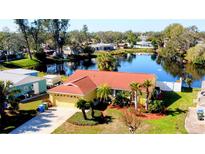 Bright yellow single-Gathering home with an attached garage and red roof, set against a backdrop of a serene pond at 3710 61St W St, Bradenton, FL 34209