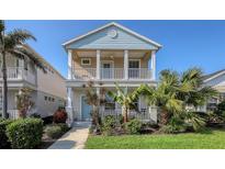Two-story house with light blue and beige exterior, front porch, and tropical landscaping at 6432 Autumn Woods Way, Sarasota, FL 34243