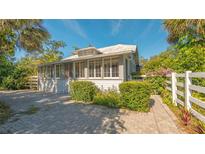 Charming bungalow with white exterior, lush landscaping, and a brick driveway at 2525 Ashton Rd, Sarasota, FL 34231