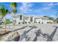 White two-story house with gray paver driveway, landscaping, and palm trees at 2287 Bayshore Rd, Nokomis, FL 34275